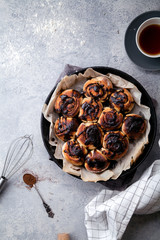 Cinnabon buns with chocolate cream on gray concrete background. Rustic styling; copy space. Vertical composition.