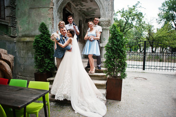 Attractive wedding couple and bridesmaids with groomsmen are having fun outdoors.