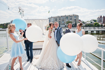 Wedding couple, groomsmen and bridesmaids having fun with balloons on wharf.