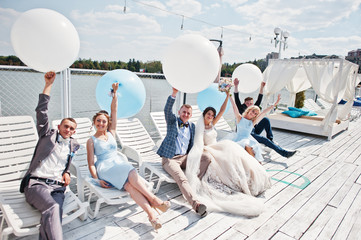 Wedding couple, groomsmen and bridesmaids having fun with balloons on wharf.