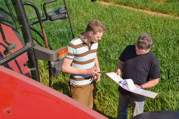 Getreideanbau - Landwirte bespricht sich mit seinem Sohn in einem Getreidefeld