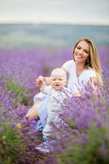 Happy mother and her little baby boy having fun in a lavender field
