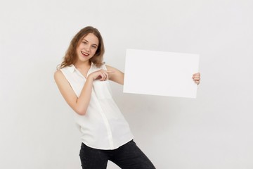 Young woman holding blank poster.Smiling woman sign board holding. Girl showing banner with copy...