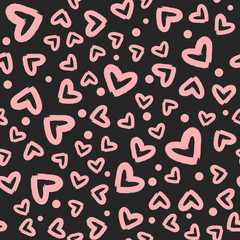 Pink hearts and dots randomly scattered on a black background. Seamless pattern. Grunge, sketch, graffiti, rough brush.
