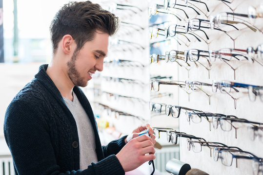 Man choosing glasses in optician shop