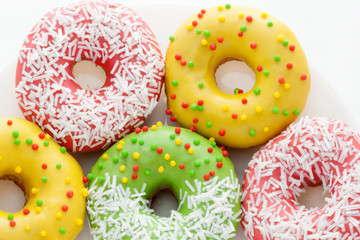 Pink, yellow and green Donuts with colored polka dots on a plate on a white background. Dessert Food. National Doughnut Day. Snacks. Fried dough confectionery.
