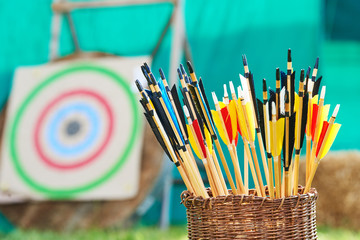 Archery concept. Basket with arrows in front of target.