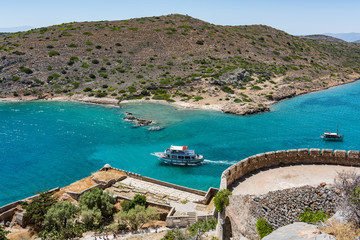 Top of Spinalonga island. View to blue aegian sea with boats and Kalydon island.