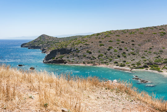 View from top of Spinalonga island. Blue sea with rocks and Kalydon island in front.