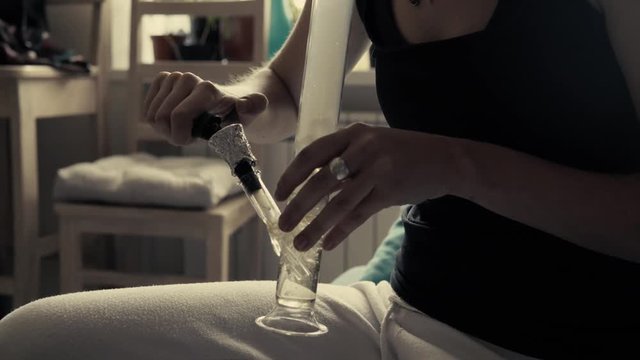 
Smoking marijuana through a glass bong close-up. Legalization of marijuana all over the world. Girl Teenager smokes marijuana in the college
