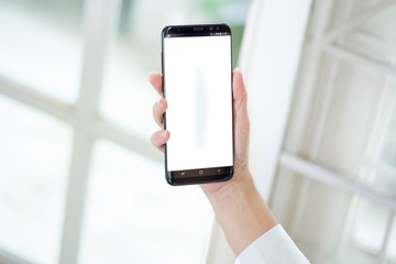 Women hands holding phone with isolated screen on background of window
