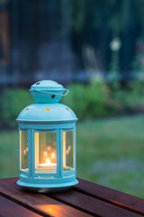 Scented candle in a pretty lantern with outdoor green background