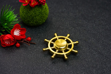 Hand spinners or fidgeting spinners. A ship's wheel alike hand spinners put on the black stone...