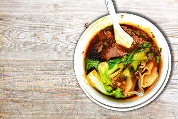 Traditional Thai soup with homemade noodles and beef on wooden table