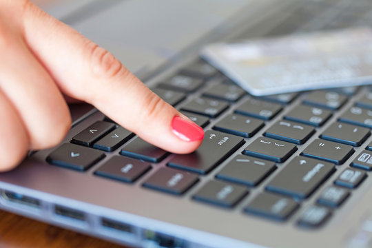 Finger pointing at Enter key, credit card lying on the keyboard - online shopping