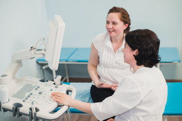 Obraz premium Doctor showing baby ultrasound image on computer to pregnant woman