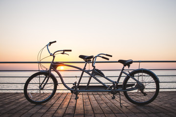 Picture of a tandem bicycle outdoor on sunset or sunrise - obrazy, fototapety, plakaty