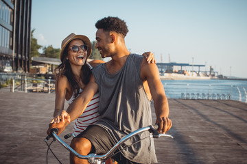 Portrait of a mixed race couple on tandem bicycle outdoors near the sea - 164107696