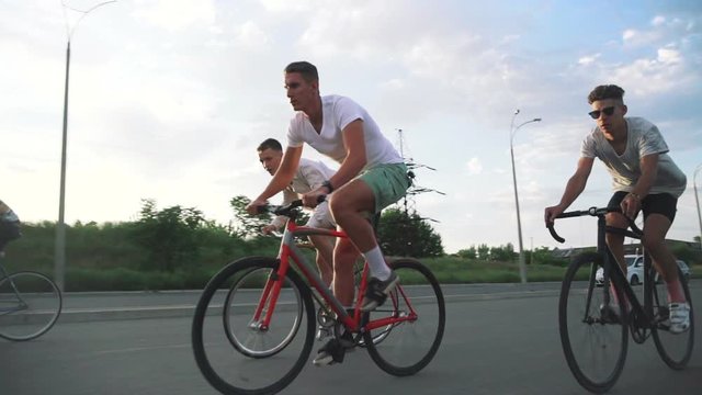 Group of cyclists riding fixed gear bikes on the road, steadycome shot, slow motion