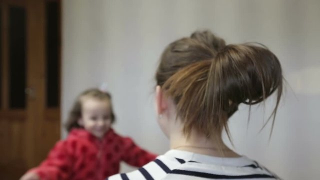 Daughter rushes into mother's arms at home and gives her a big hug.