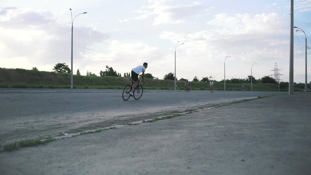 Young hipster man sliding on fixed gear bicycle in dust on the road, slow motion