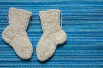 Вязаные белые детские носочки на бирюзовом фоне
