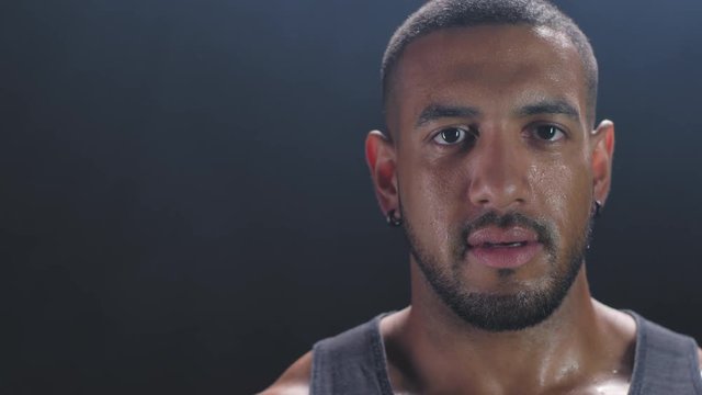 Portrait Shot Of A Muscular Black Man Catching His Breath On A Foggy Dark Background.