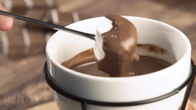 Fondue. marshmallow being dipped in chocolate