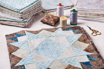 Fototapeta na wymiar Prepared blocks for sewing quilt, stack of fabrics, sew accessories