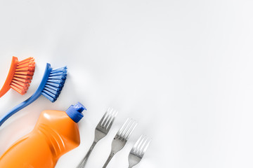 Dishwashing liquid, tableware and brushes on white background top view copyspace