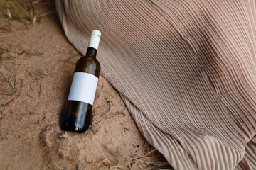 Red wine bottle with white label on the beach sand.