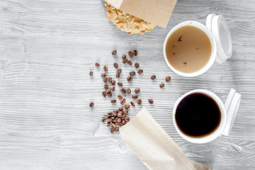 Coffee to go. Coffee cups with cover and coffee beans on wooden table backound top view