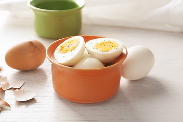 Bowl with sliced hard boiled eggs on light background. Nutrition concept
