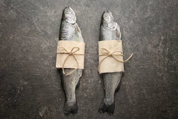 Papier Peint photo Poisson Fresh trout fish wrapped in paper on gray background