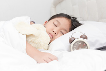cute little asian girl sleep and hug doll on bed