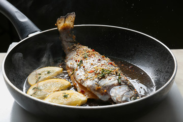 Cooking trout fish on frying pan, closeup