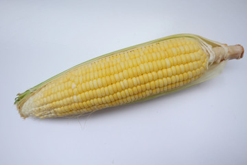 Closeup fresh sweet corn pods and corn kernels on wooden basket.