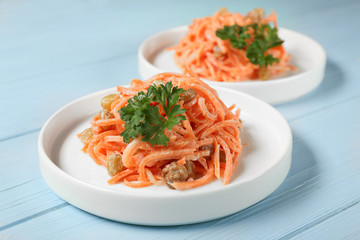 White plates with yummy carrot raisin salad on blue wooden table