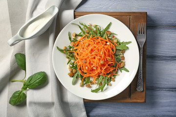 Delicious carrot raisin salad with greens on wooden table, top view