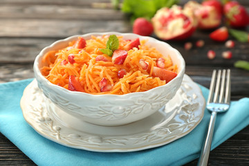Yummy carrot strawberry salad in beautiful bowl on wooden table