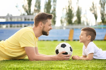 Naklejka premium Dad and son with soccer ball in stadium