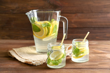 Jars and jug of fresh lemonade on wooden background