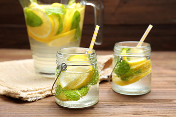 Jars and jug of fresh lemonade on wooden background