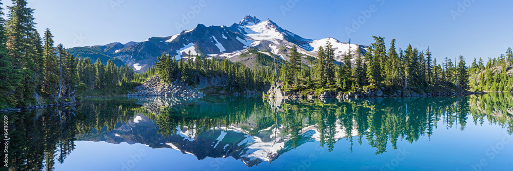 Wall mural volcanic mountain in morning light reflected in calm waters of lake.