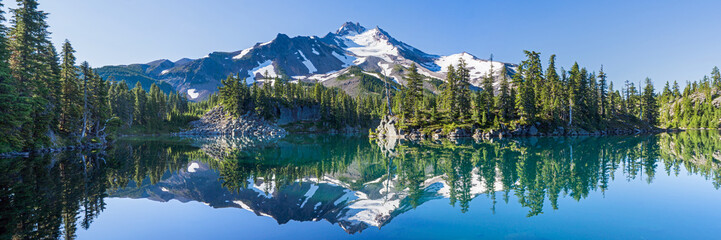 Panele Szklane  Wulkaniczna góra w porannym świetle odbita w spokojnych wodach jeziora.