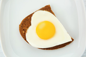 Plate with delicious sunny side up egg and bread slice, closeup