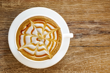 Top view of hot coffee caramel macchiato cup on wood table background.