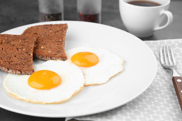 Plate of homemade over easy fried eggs with bread and cup of tea on table