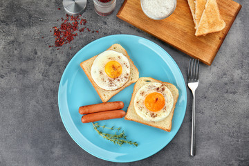 Fototapeta na wymiar Toasts with sunny side up eggs and sausages on plate