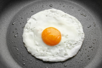 Tasty over easy fried egg in pan, closeup